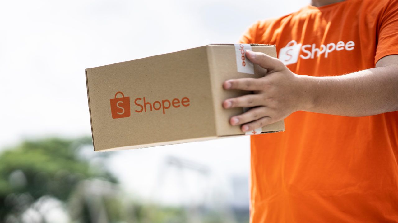 Um homem vestindo a camiseta da Shopee entregando um pacote.