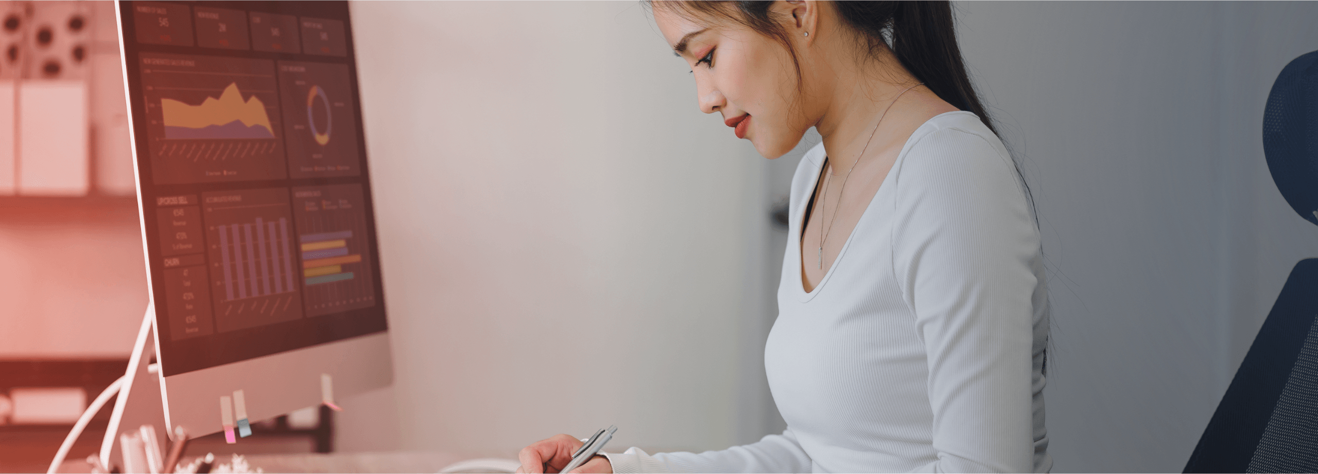 Mulher trabalhando em um escritório, analisando gráficos e fazendo anotações em um caderno, representando a importância da gestão de franquia.