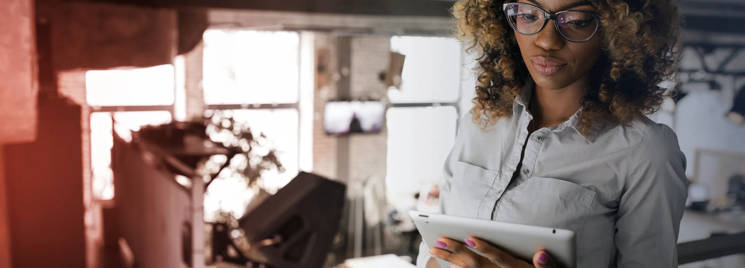 Uma mulher com um tablet nas mãos, dentro de uma loja de roupas.